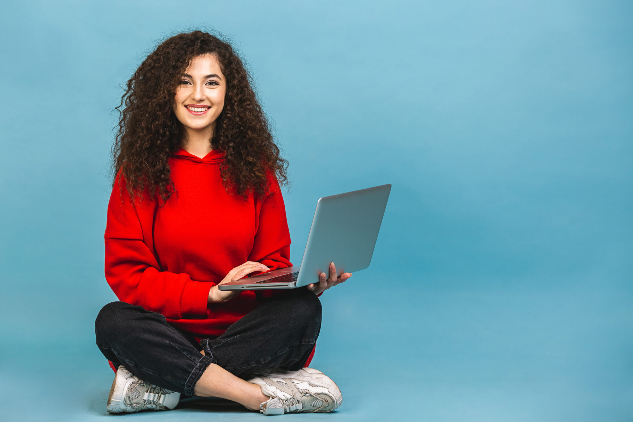 Curly beautiful woman sitting on the floor with laptop
