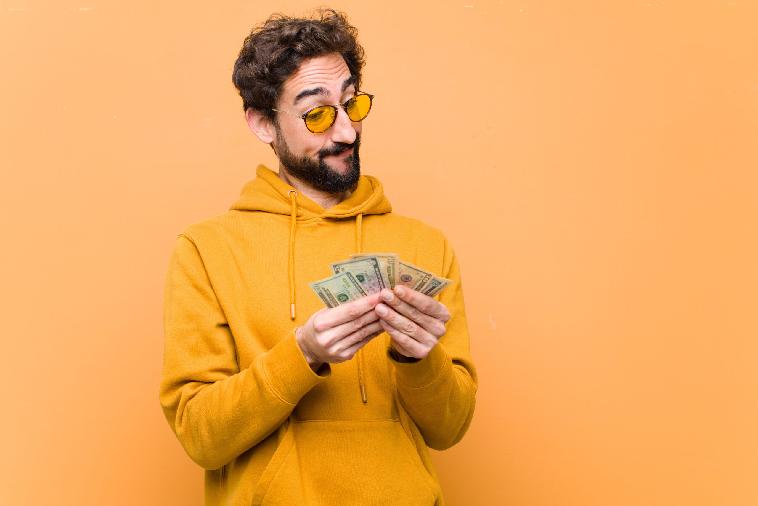 young crazy cool man with dollar banknotes against orange wall
